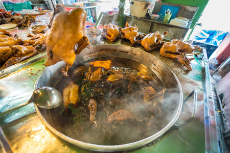 close-up view of whole ducks being cooked in a large pot filled with steaming broth, capturing the essence of traditional Asian market cuisine.の写真素材