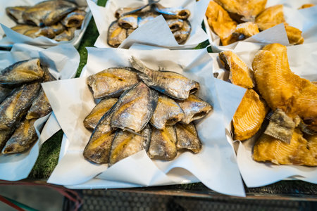 Various types of crispy fried fish fillets neatly arranged on paper in a local seafood market, highlighting their golden-brown color.の写真素材