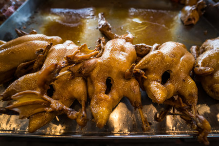 A close-up of golden brown roasted ducks hanging in a traditional market setting, perfect for showcasing culinary traditions.の写真素材