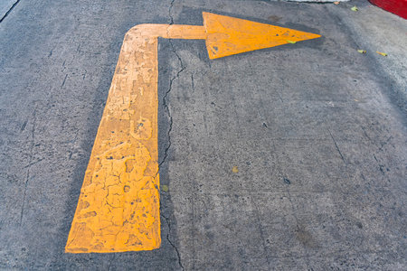 A weathered yellow arrow on a cracked concrete surface, representing guidance and the passage of time.の写真素材