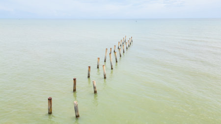 Discover the serenity of the beach with old posts jutting out of calm waters, providing a perfect backdrop for meditation, photography, or simply enjoying the beauty of nature.の写真素材