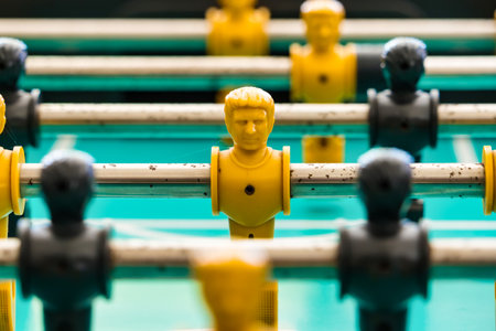 Close-up view of yellow and black foosball players on a green game table, representing teamwork, strategy, and fun in a classic table soccer match.の写真素材