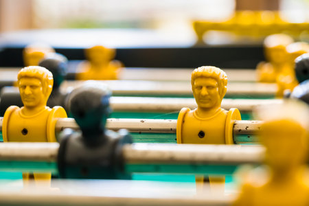 Close-up view of yellow and black foosball players on a green game table, representing teamwork, strategy, and fun in a classic table soccer match.の写真素材