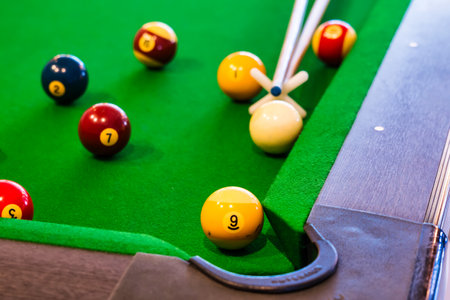 The image shows colorful numbered billiard balls arranged on a green felt pool table with a cue...