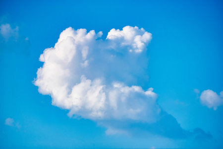 This captivating image showcases a breathtaking scene of fluffy, white clouds drifting gracefully across a vibrant blue sky, creating a serene and calming atmosphere.の写真素材