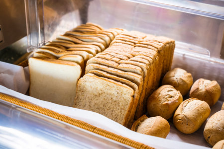 An enticing display of various freshly baked bread and rolls in a bakery's showcase, perfect for gourmet and everyday meals.の写真素材