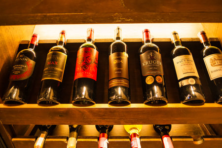 Chonburi, Thailand - November, 18, 2024: An Artful Arrangement of Red Wines in a Refined Wooden Display for Wine Lovers at Chonburi, Thailand.のeditorial素材