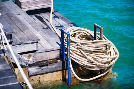 A rustic wooden dock with a coiled rope by the turquoise sea.の写真素材