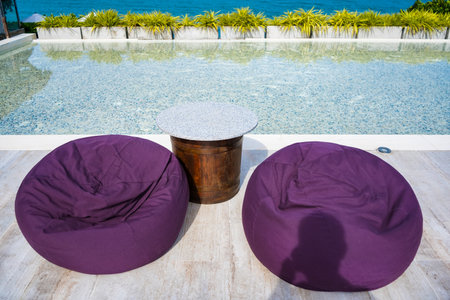 A contemporary outdoor seating area with curved wooden platforms, blue cushioned benches, and small wooden tables, surrounded by lush greenery for a relaxing ambiance.の写真素材