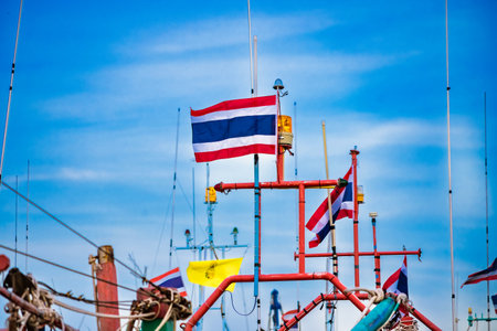 Thai fishing boats adorned with national flags against a clear blue sky.の写真素材