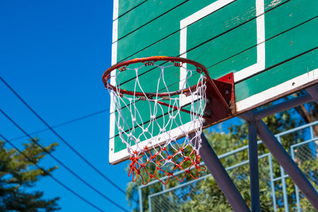 Outdoor Basketball Hoop with Green Wooden Backboard and Blue Sky Background, Perfect for...