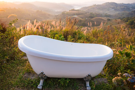 Serene Outdoor Bathtub with Scenic Mountain View at Sunrise: Experience Ultimate Relaxation Surrounded by Nature's Beauty in a Tranquil Settingの写真素材