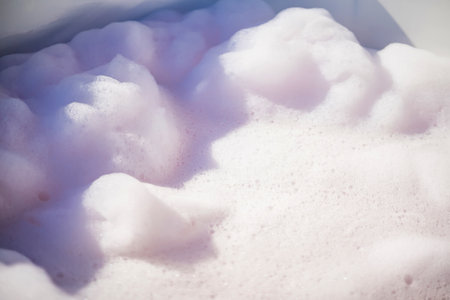 Fluffy White Soap Foam Floating in a bathtub Under Sunlight, Perfect for Spa, Wellness, and Relaxation-Themed Concepts in a Natural Settingの写真素材