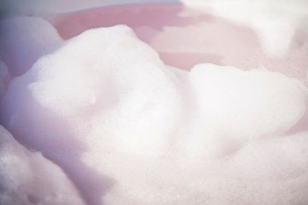 Fluffy White Soap Foam Floating in a bathtub Under Sunlight, Perfect for Spa, Wellness, and Relaxation-Themed Concepts in a Natural Settingの写真素材