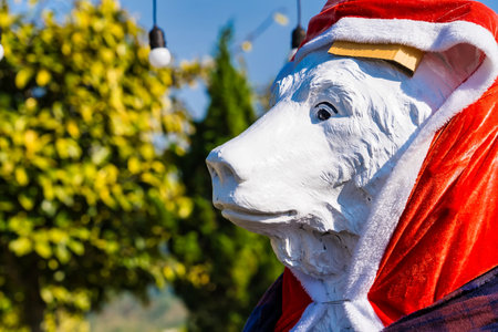 Statue of a polar bear dressed in winter clothing including a red Santa hat and scarf standing in a garden settingの写真素材