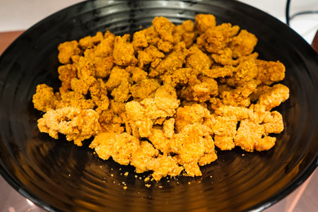 A large black bowl filled with crispy golden fried chicken pieces ready to be served as a delicious snack or mealの写真素材