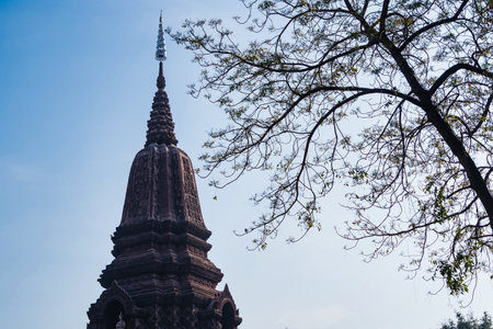 Lop Buri, Thailand - January, 02, 2025 : Ancient stone temple with intricate carvings and steep pagoda structure against a clear blue sky at Lop Buri, Thailandの写真素材