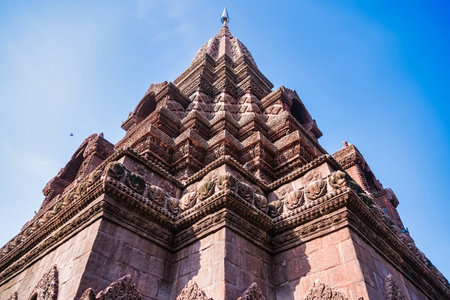 Lop Buri, Thailand - January, 02, 2025 : Ancient stone temple with intricate carvings and steep pagoda structure against a clear blue sky at Lop Buri, Thailandの写真素材
