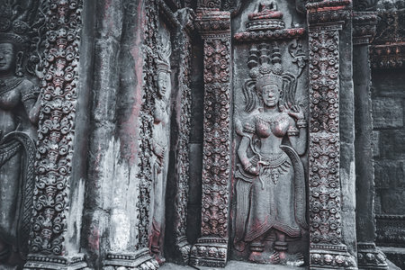 Lop Buri, Thailand - January, 02, 2025 :Ancient stone carvings of Apsara dancers with intricate details and ornate patterns on temple walls at Lop Buri, Thailand.の写真素材
