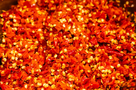Close-up image of finely chopped red chili peppers with visible seeds creating a vibrant and spicy textureの写真素材
