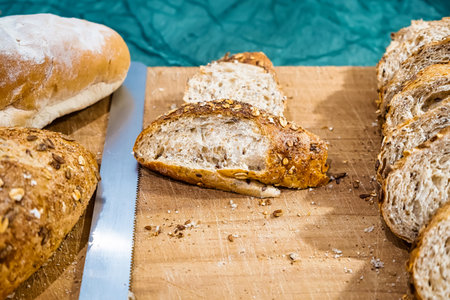 Sliced whole grain bread arranged on a wooden board with visible bread crumbs and a blue background
