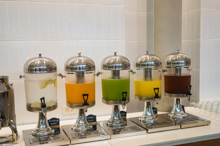 Row of stainless steel beverage dispensers with different fruit juices at a buffet breakfast stationの写真素材