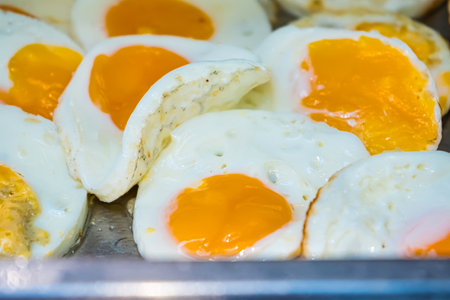 Close-up of several fried eggs with runny yolks and white edges cooked on a panの写真素材