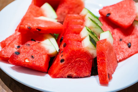 Close-up of sliced watermelon on a white plate showcasing fresh and juicy texture with seeds visibleの写真素材