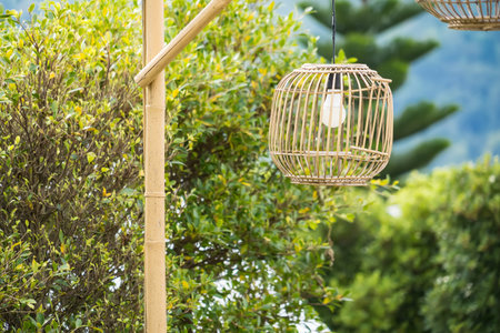 Two bamboo lanterns hanging outdoors with a lush green mountainous backdrop creating a serene and natural ambianceの写真素材