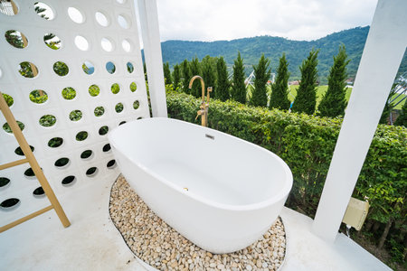 Phetchabun, Thailand - June, 06, 2025 :Outdoor freestanding bathtub surrounded by lush greenery and pebbles with mountain view in the background at Phetchabun, Thailandの写真素材
