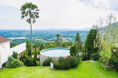 Phetchabun, Thailand - June, 08, 2025 :Scenic view of a luxury infinity pool overlooking a lush green valley and distant mountains on a sunny day at Phetchabun, Thailandの写真素材