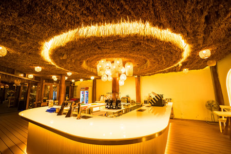 Phetchabun, Thailand - June, 08, 2025 : Cozy outdoor lounge area with woven lampshades and rustic decor under a wooden roof illuminated at night at Phetchabun, Thailandの写真素材