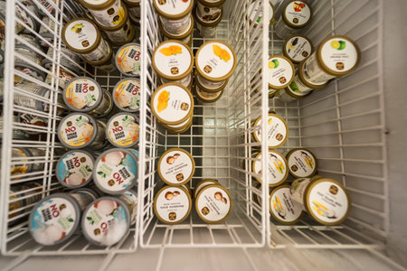 Phetchabun, Thailand - June, 08, 2025 : Ice cream containers neatly organized in a freezer display viewed from above with various flavors visible on the lids at Phetchabun, Thailandの写真素材