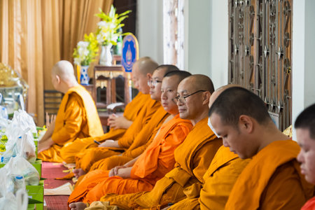 Chiang Mai, Thailand - July, 18, 2025 : A group of Buddhist monks in orange robes sitting in a temple during a religious ceremony, engaging in meditation and prayer at Chiang Mai, Thailand.の写真素材
