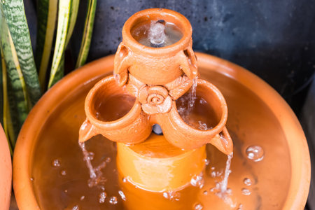 Decorative terracotta fountain with flowing water from handcrafted clay pots in a peaceful indoor or garden settingの写真素材