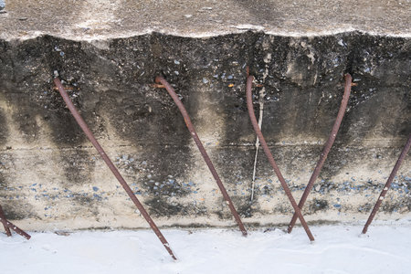 Exposed rusty steel reinforcement bars sticking out from a weathered concrete wall at a construction or demolition siteの写真素材