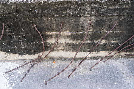 Exposed rusty steel reinforcement bars sticking out from a weathered concrete wall at a construction or demolition siteの写真素材