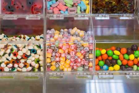 Assorted colorful candies on display in clear plastic bins at a self-serve candy store or confectionery shopの写真素材