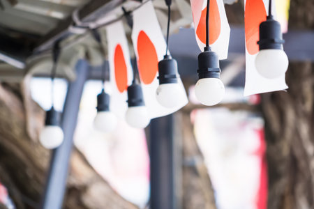 Close-up of hanging light bulbs and Japanese flags used as decorations for a festival or outdoor eventの写真素材