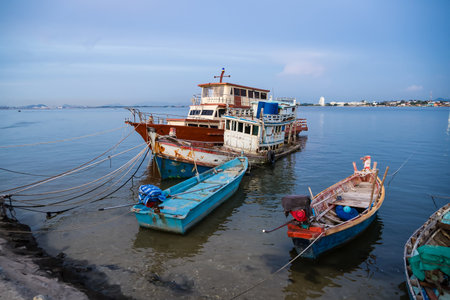 Traditional wooden fishing boats docked in a calm harbor with ropes and nets visible during a peaceful seaside dayの写真素材