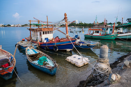 Traditional wooden fishing boats docked in a calm harbor with ropes and nets visible during a peaceful seaside dayの写真素材