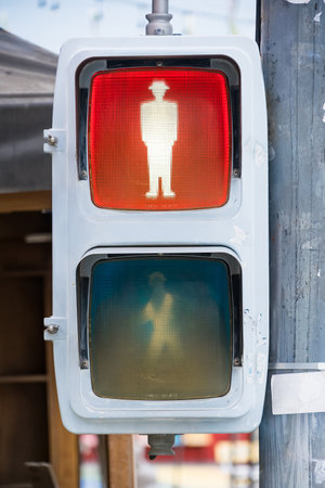 Close-up of a pedestrian traffic light showing a red stop signal with a stylized male figure wearing a hatの写真素材