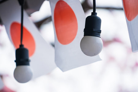 Close-up of hanging light bulbs and Japanese flags used as decorations for a festival or outdoor eventの写真素材