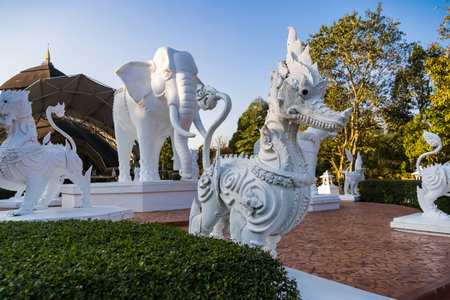 Chiang Mai, Thailand - January, 06, 2026 : Decorative white dragon statues with intricate carvings in an outdoor setting surrounded by green foliage and trees at Chiang Mai Thailand.の写真素材