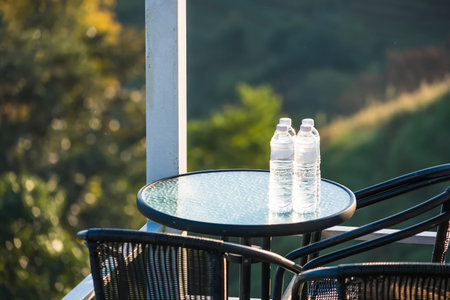 Refreshment with a View: Two cool, refreshing water bottles sit on a glass table. The outdoor patio creates the perfect setting for a moment of hydration.の写真素材