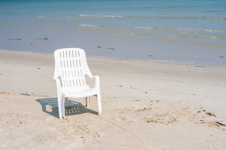 Solitary chair on Beach: A lone white chair sits peacefully on the sandy shore, inviting a moment of...