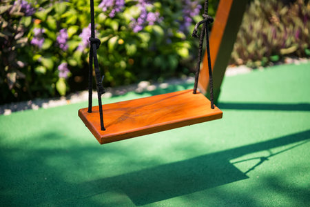 Serene swing set in the sun: A wooden swing set, basking in the sun's warm glow, hangs peacefully....