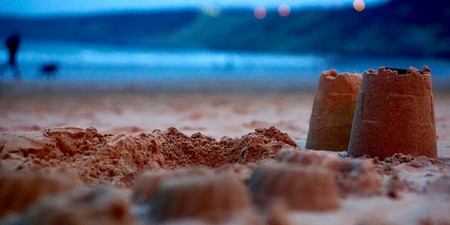 Sand castles, a man walking his dog in the background.の写真素材