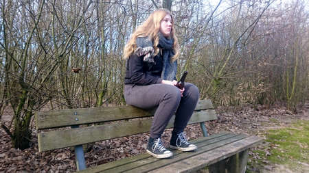 Teenager sits with a beer bottle on the back of a park bench with blank look into the distanceの写真素材