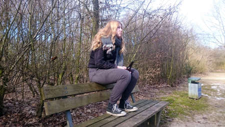 Teenage boy sits with a beer bottle on the back of a park bench, side viewの写真素材